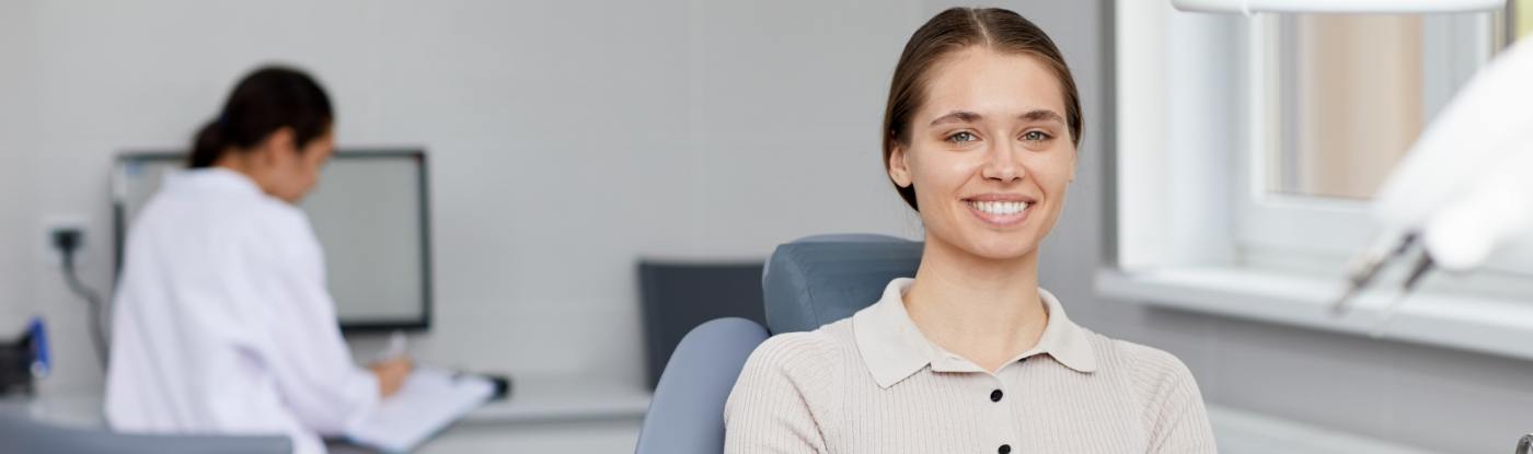 Woman smiling in dental chair with dental team member in background
