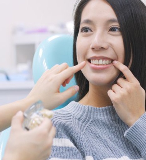Woman smiling and pointing at her teeth for her dentist