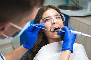 Dentist examining and cleaning his patient’s teeth