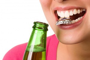 Close up of woman using her teeth to open a bottle